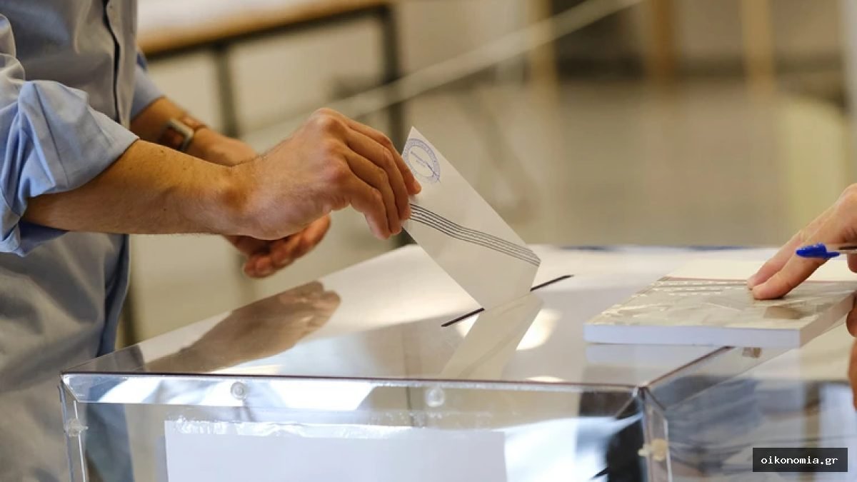 Χέρια ψηφοφόρων με ψηφοδέλτιο πάνω από διαφανή κάλπη.