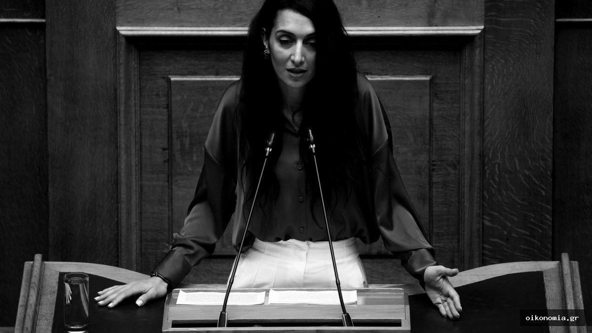 Η Κατερίνα Σπυριδάκη στο βήμα της Βουλής, μπροστά σε δύο μικρόφωνα.