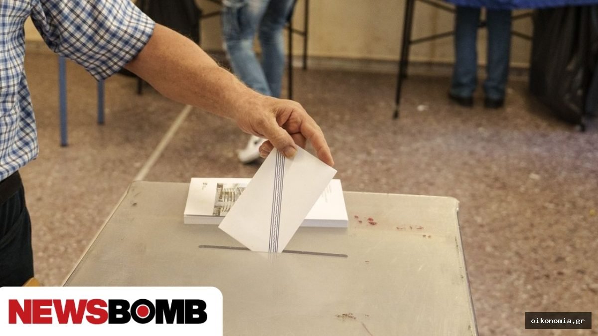 Χέρι τοποθετεί λευκό ψηφοδέλτιο σε κάλπη σε εκλογικό τμήμα.
