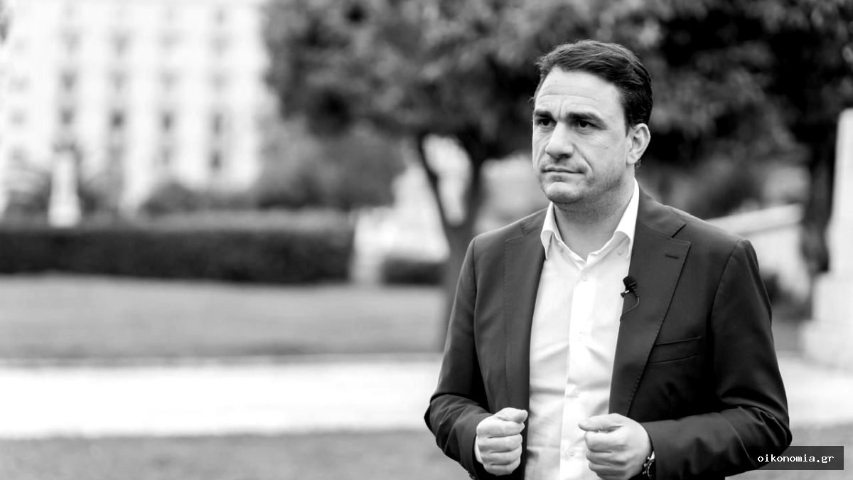 Ο Κώστας Τσουκαλάς, με μπλε σακάκι και λευκό πουκάμισο, σε εξωτερικό χώρο.