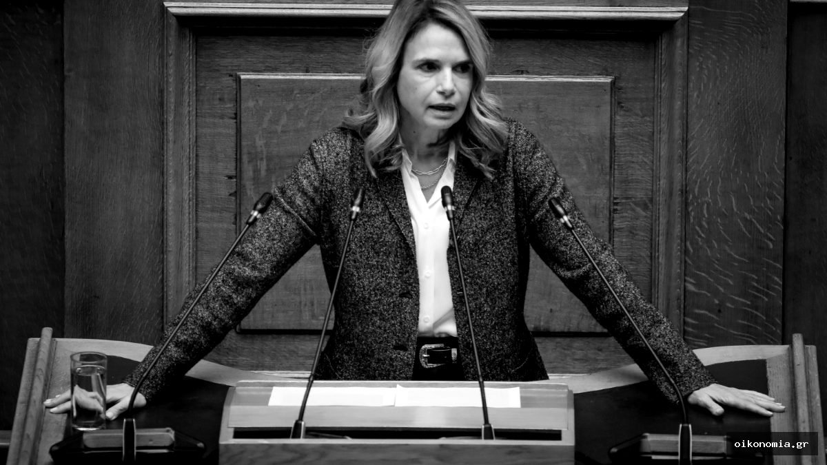 Η Μιλένα Αποστολάκη στο βήμα της Βουλής, μπροστά σε μικρόφωνα.