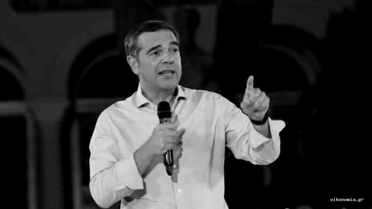 Ο Αλέξης Τσίπρας μιλά σε συγκέντρωση κρατώντας μικρόφωνο.